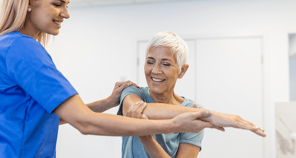 Physical therapist assisting elderly woman with exercise.
