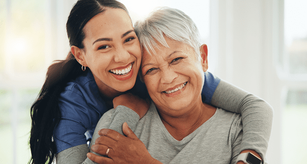 Smiling women embracing each other happily.